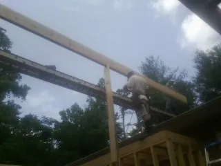 Carpenter setting a ridge beam over a new addition frame — Ice Dam Removal by Roofing Brothers in Mount Olivet