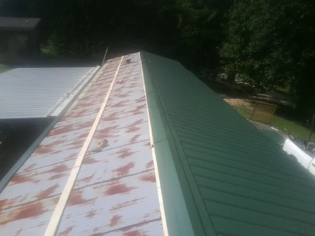 Old rusted panels beside newly installed green metal roofing — Wind Damage Roof Repair by Roofing Brothers in Mount Olivet