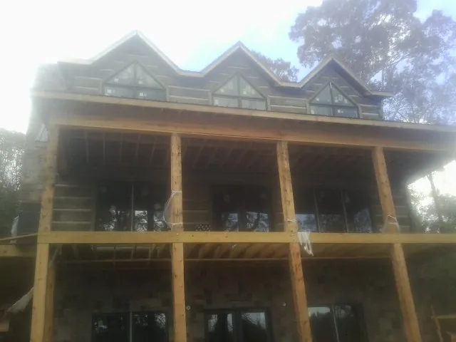 Dormers and porch framing on a large log home under construction — Roof Coating work by our crew in Mount Olivet