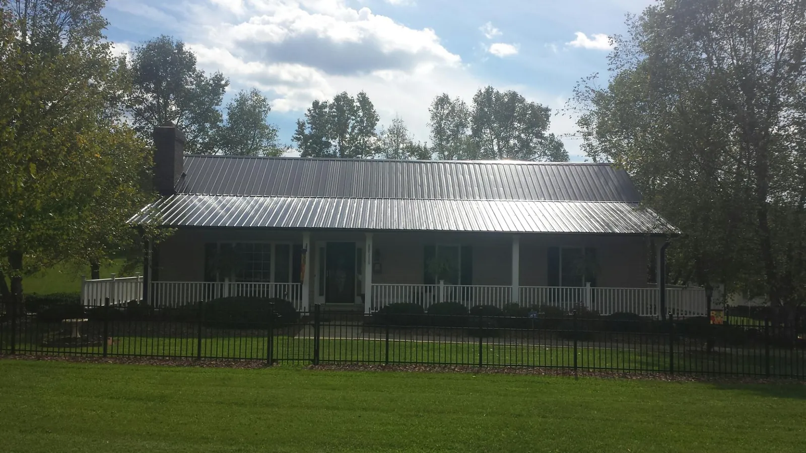 Gray metal roof on a brick ranch with a full width front porch — Gutter Guard Installation work by our crew in Mount Olivet