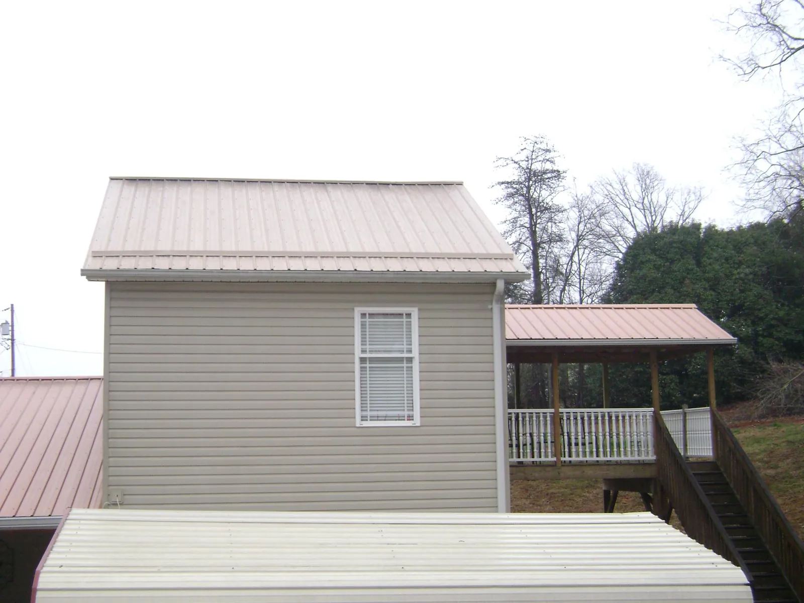 Tan metal roofs on a two story addition and attached porch, from a Roof Replacement job in Mount Olivet